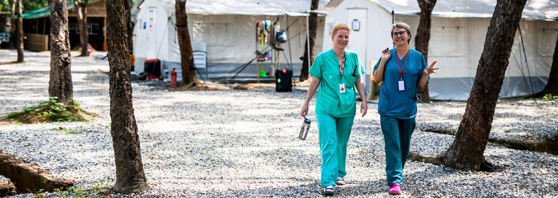 Two delegates talking and walking. Behind them are big white tents.