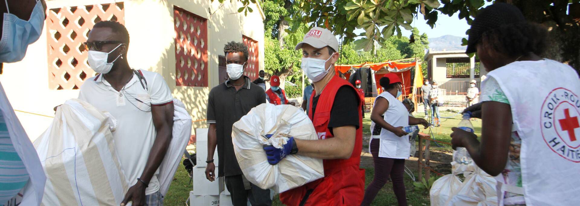 Red Cross volunteers walking with big bags in their hands in Haiti.