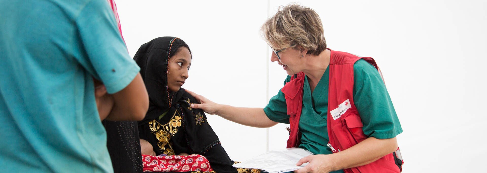 A delegate holds their hand on a patients shoulder at a hospital in Cox Bazaar.