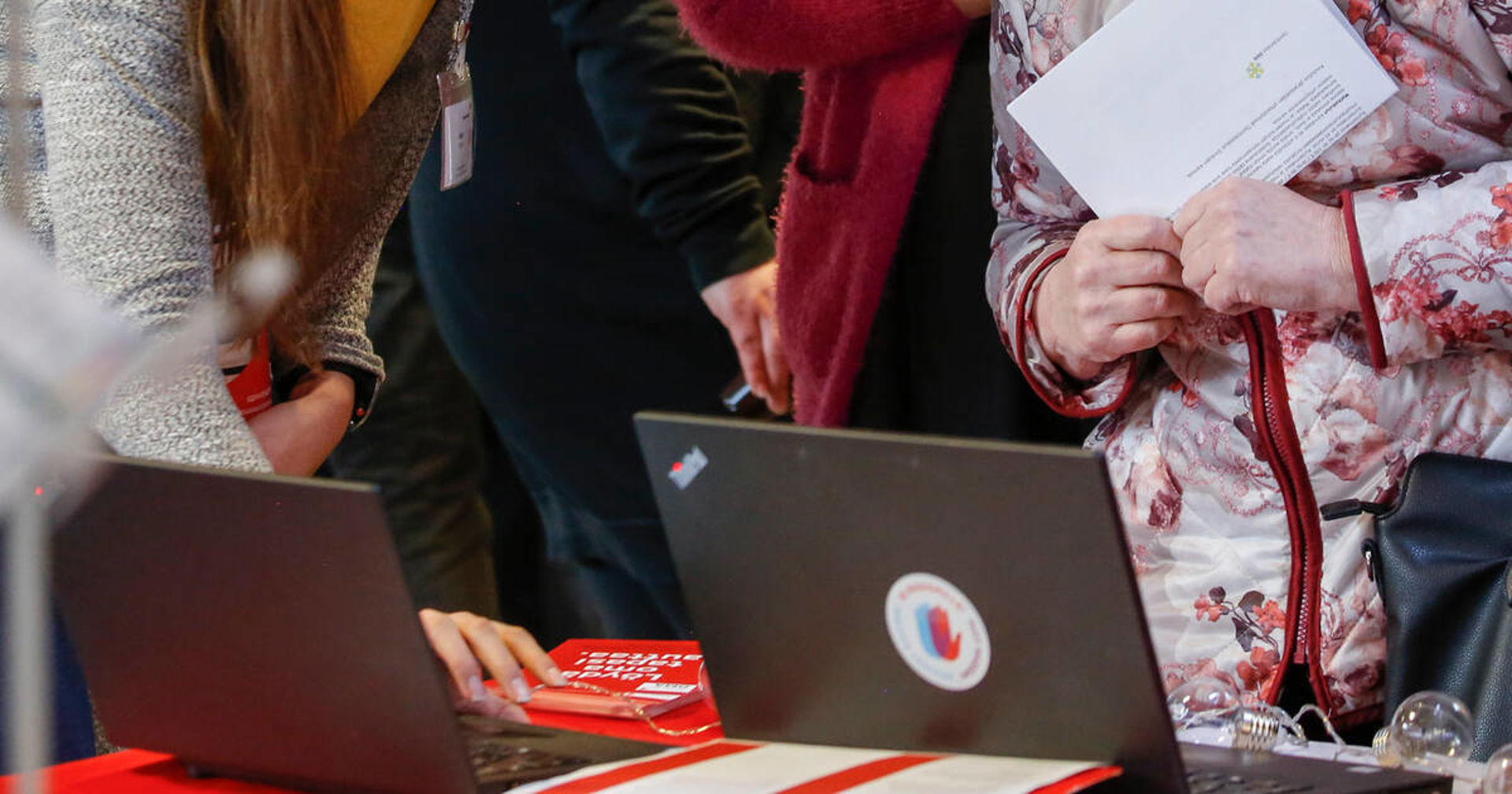 Three people are leaning over a computer.