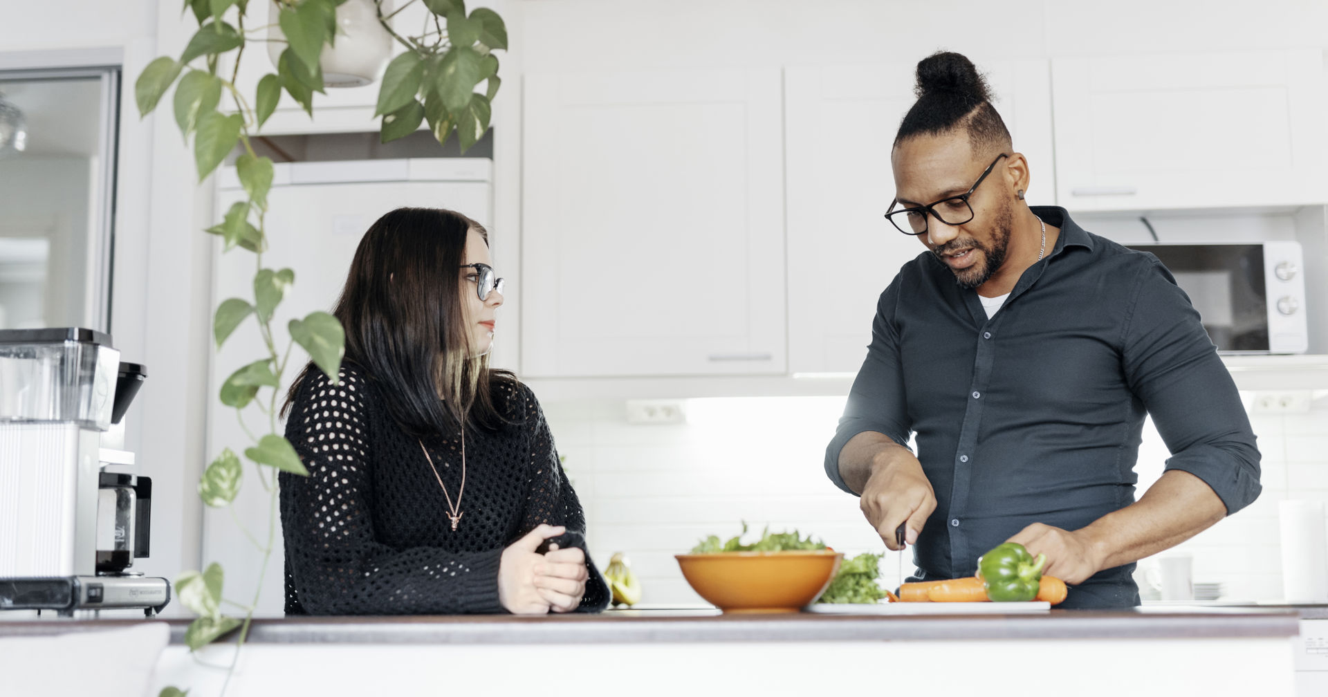 Two people are chatting in the kitchen.