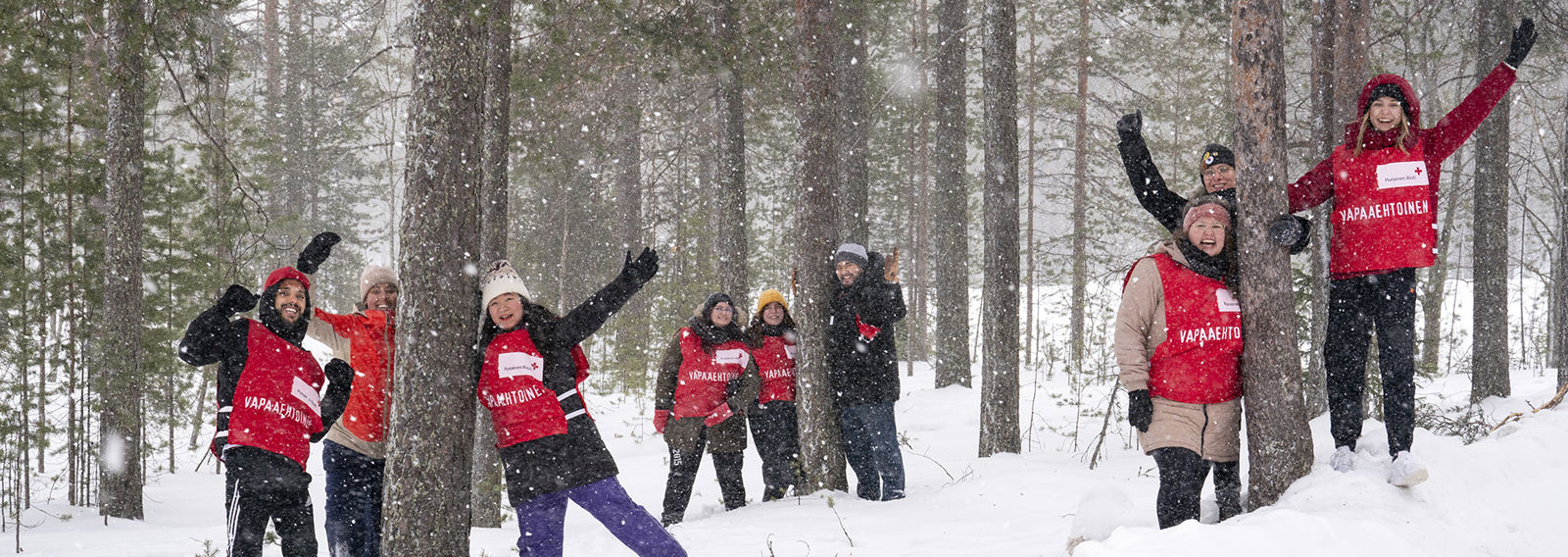 A group of volunteers waves to the camera in a snowy landscape.