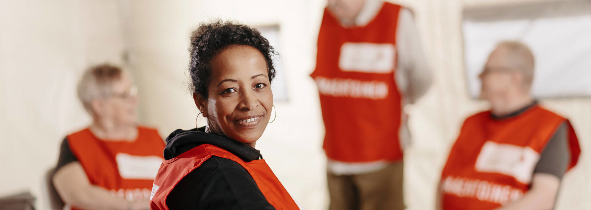 A group photo of people in a circle, in the foreground a smiling person looks at the camera.