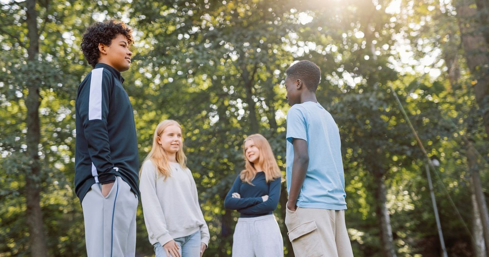 Four young people are chatting outside at a park.