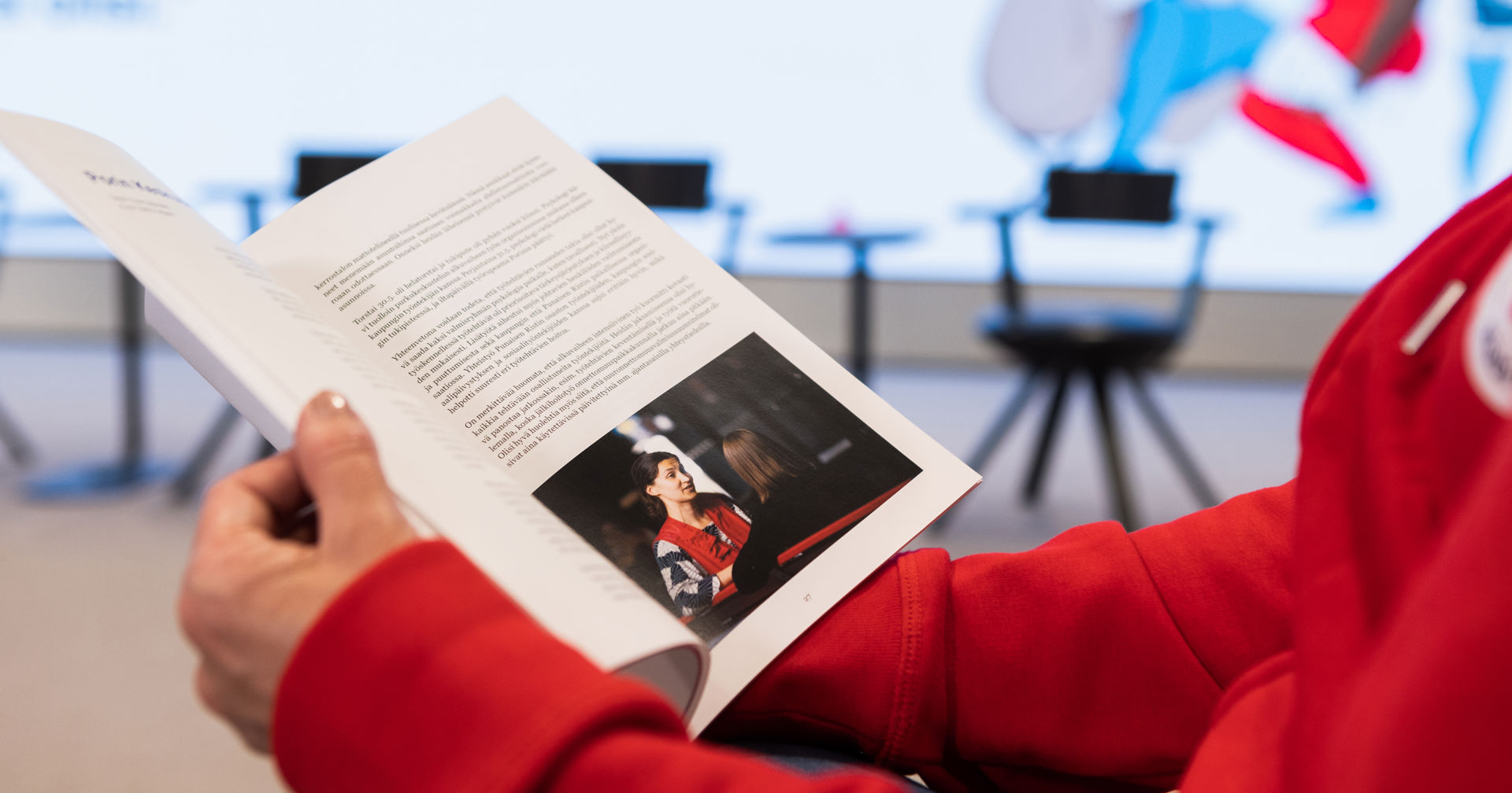 Hands are holding a brochure about the Finnish Red Cross.