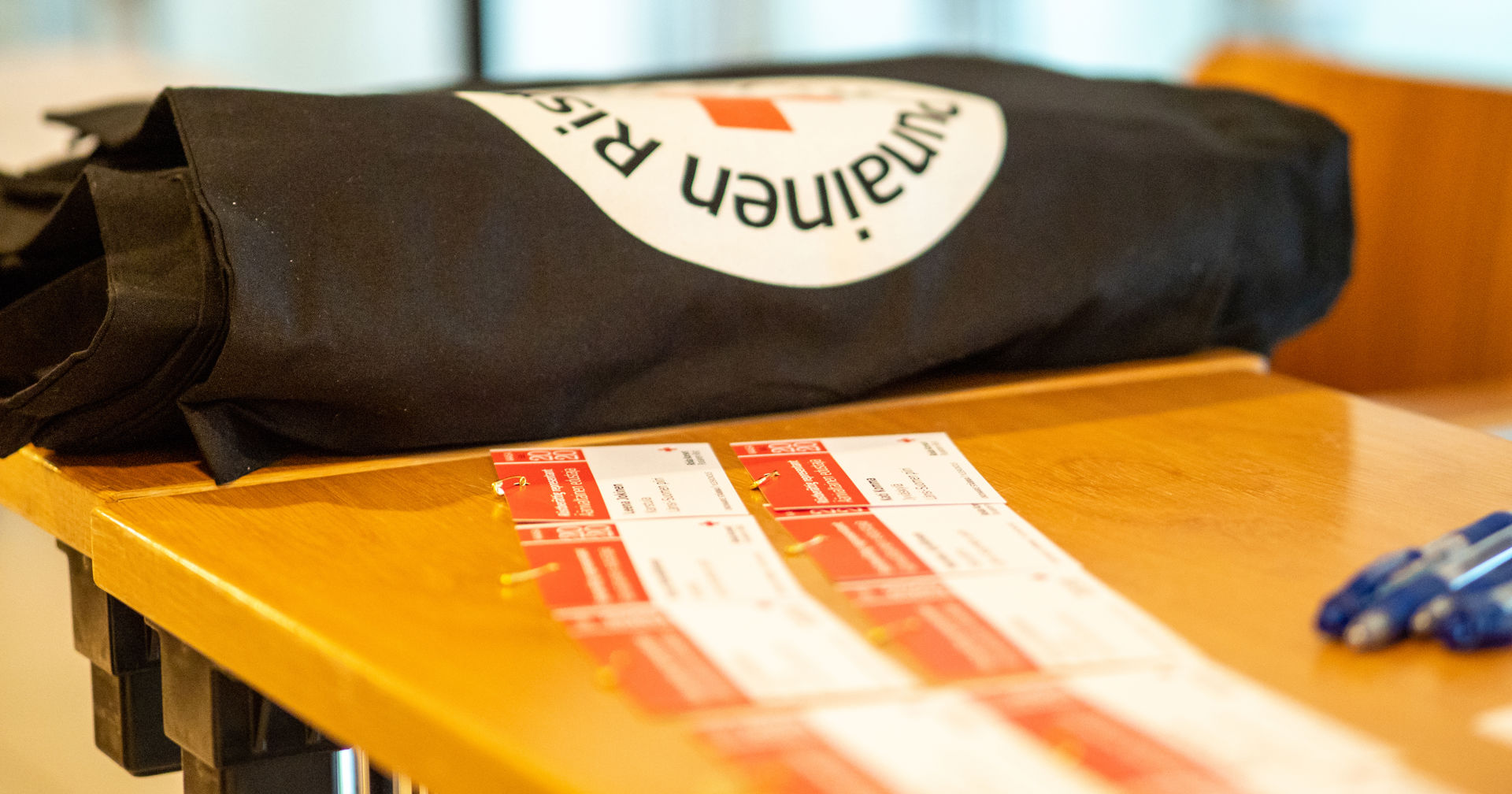 There are a bag and name tags with a Red Cross logos on a table.