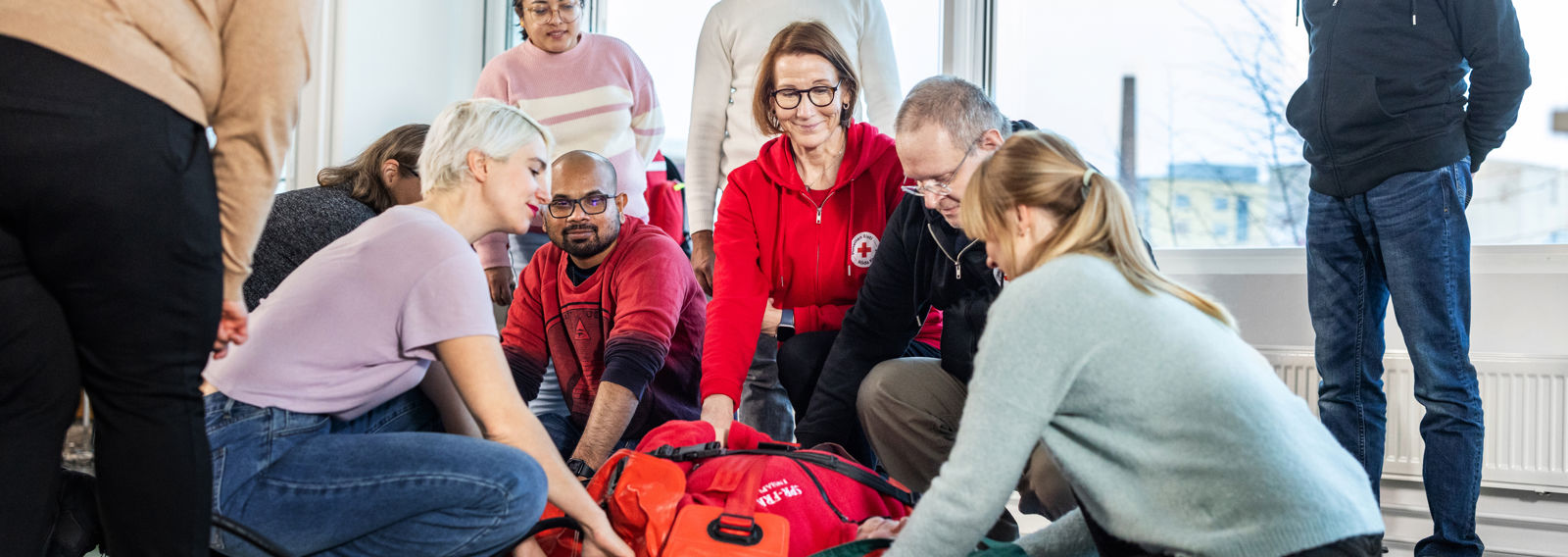 Volunteers in training crouching around a supply kit.