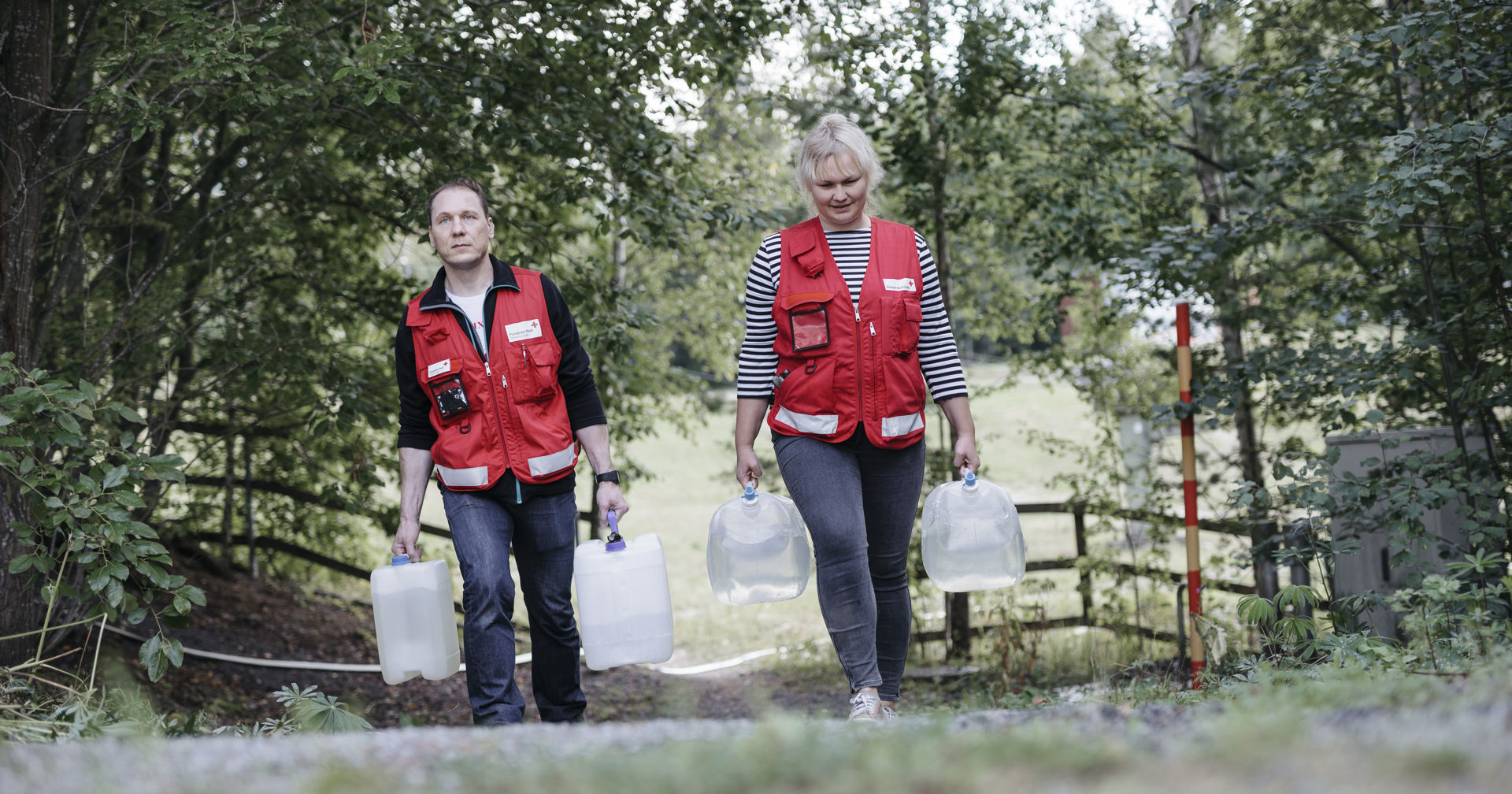 Two volunteers carrying water containers.