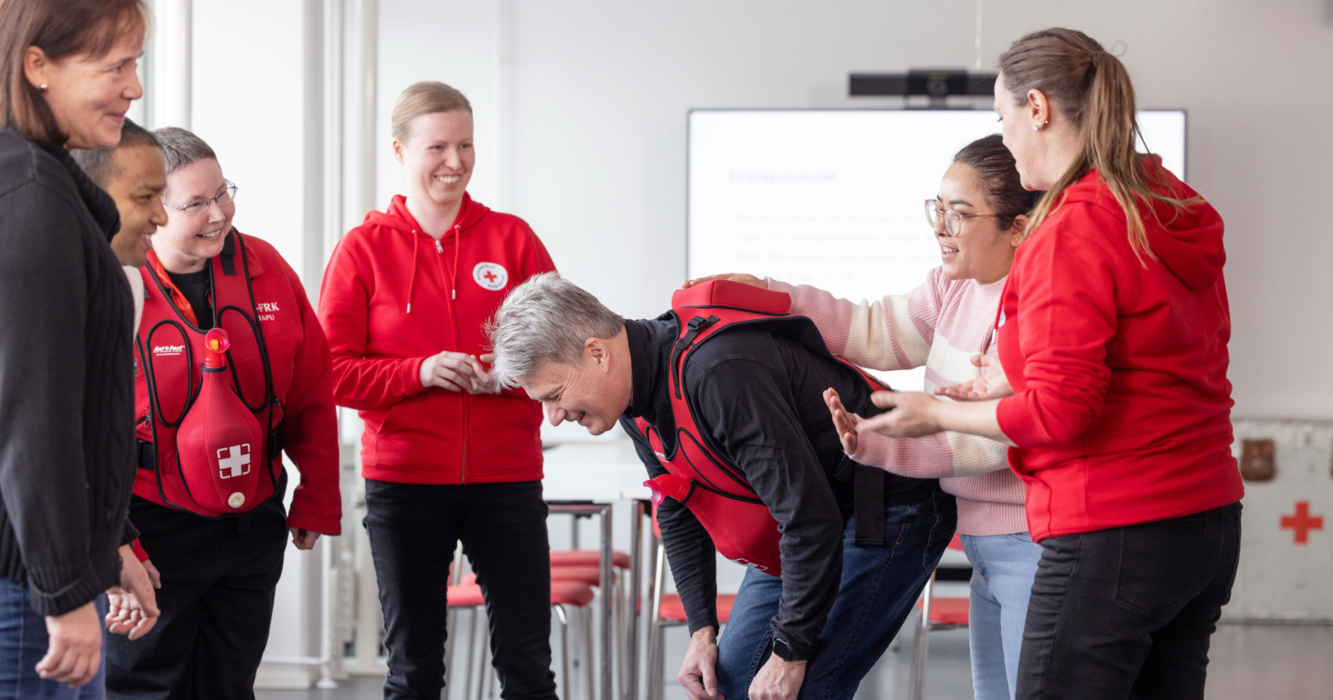 Volunteers smiling in a circle. One is leaning forward in the center.