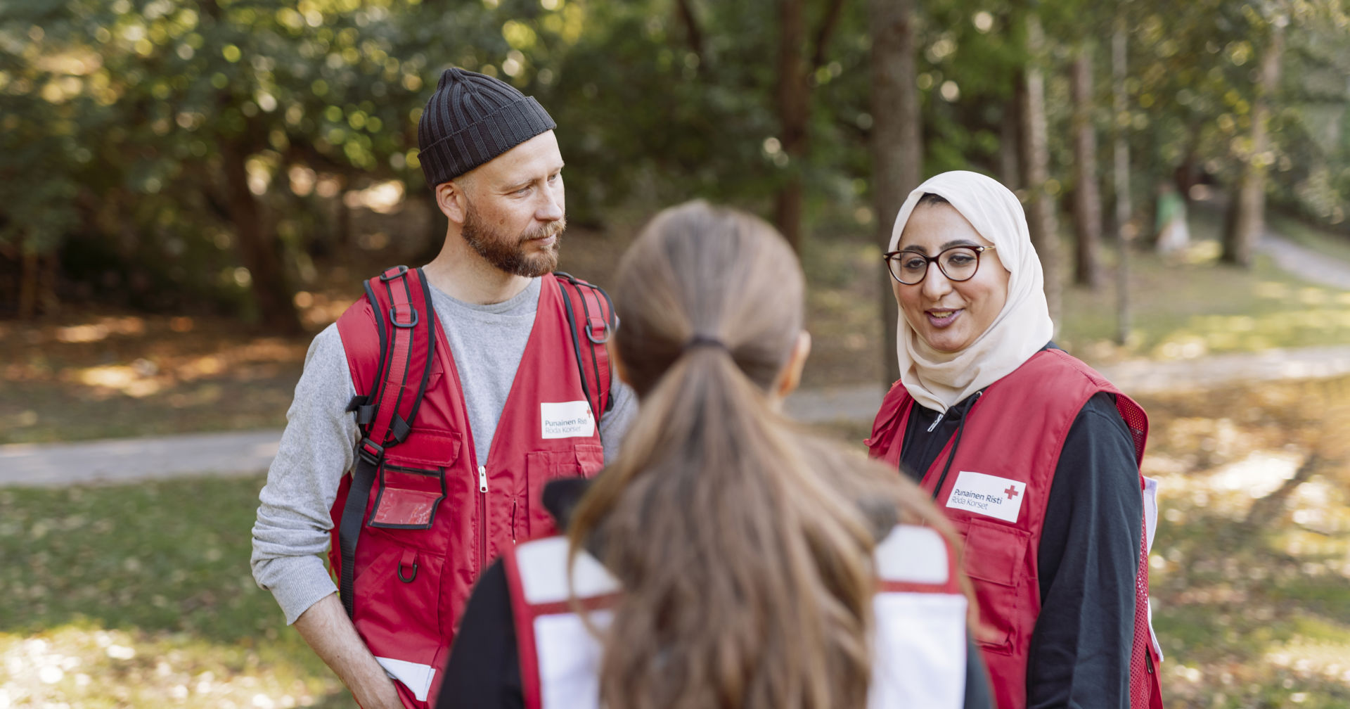 Three volunteers chatting in a park.