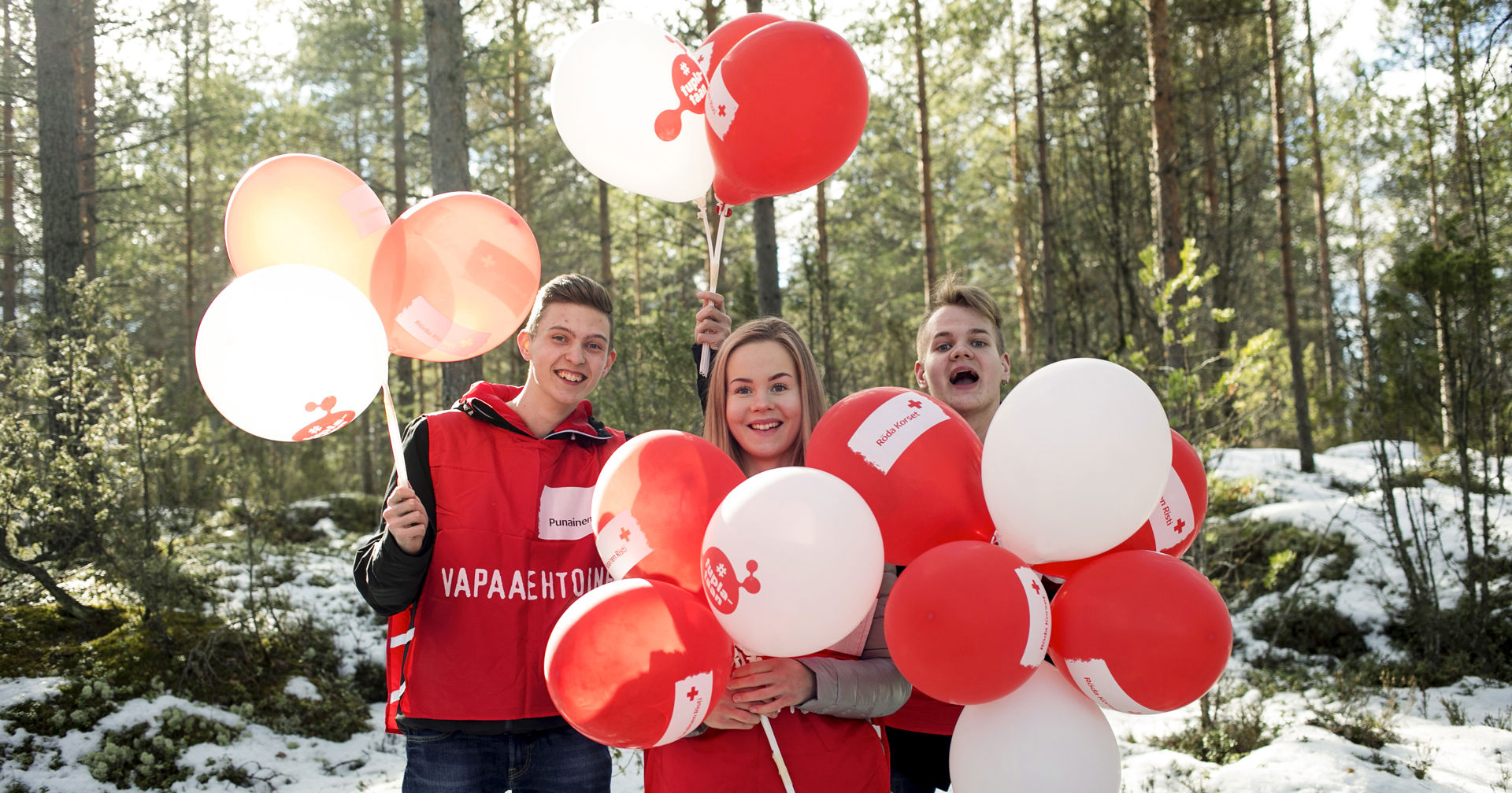 Three young volunteers smiling with balloons.