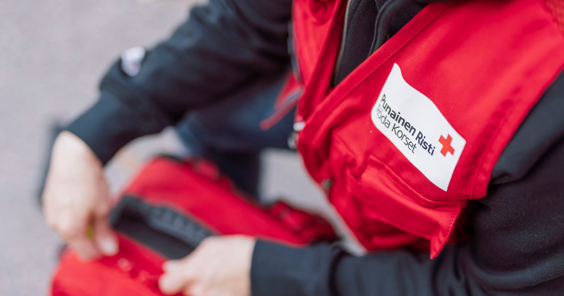 A Red Cross volunteer in a vest closing a first aid kit.