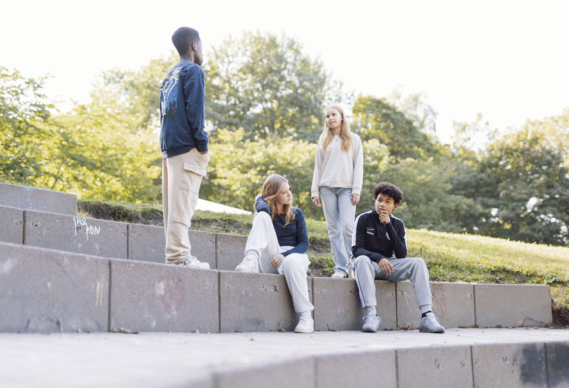 The young people are sitting outside on the steps.