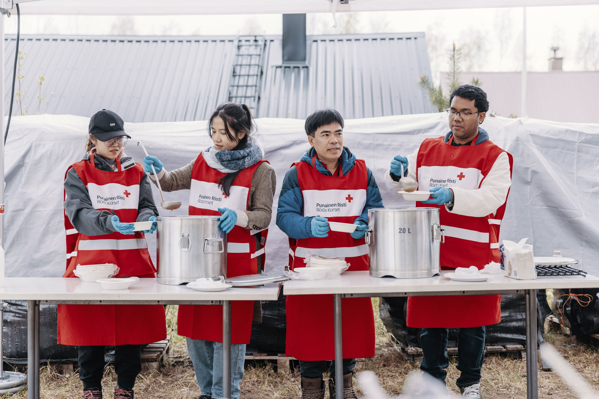Red Cross volunteers serve soup onto plates.