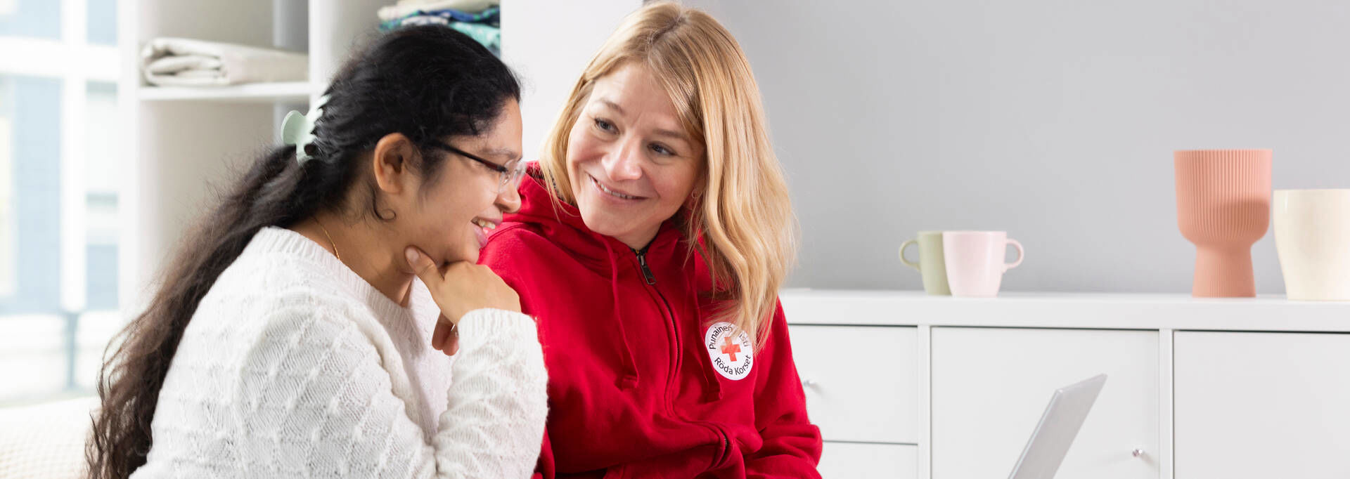 A volunteer guides the branch's new employee, who has a laptop on their lap.