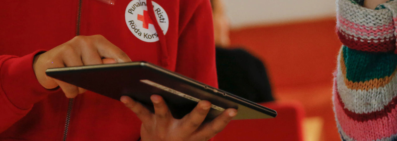 A person is holding a tablet device and showing it to another person.