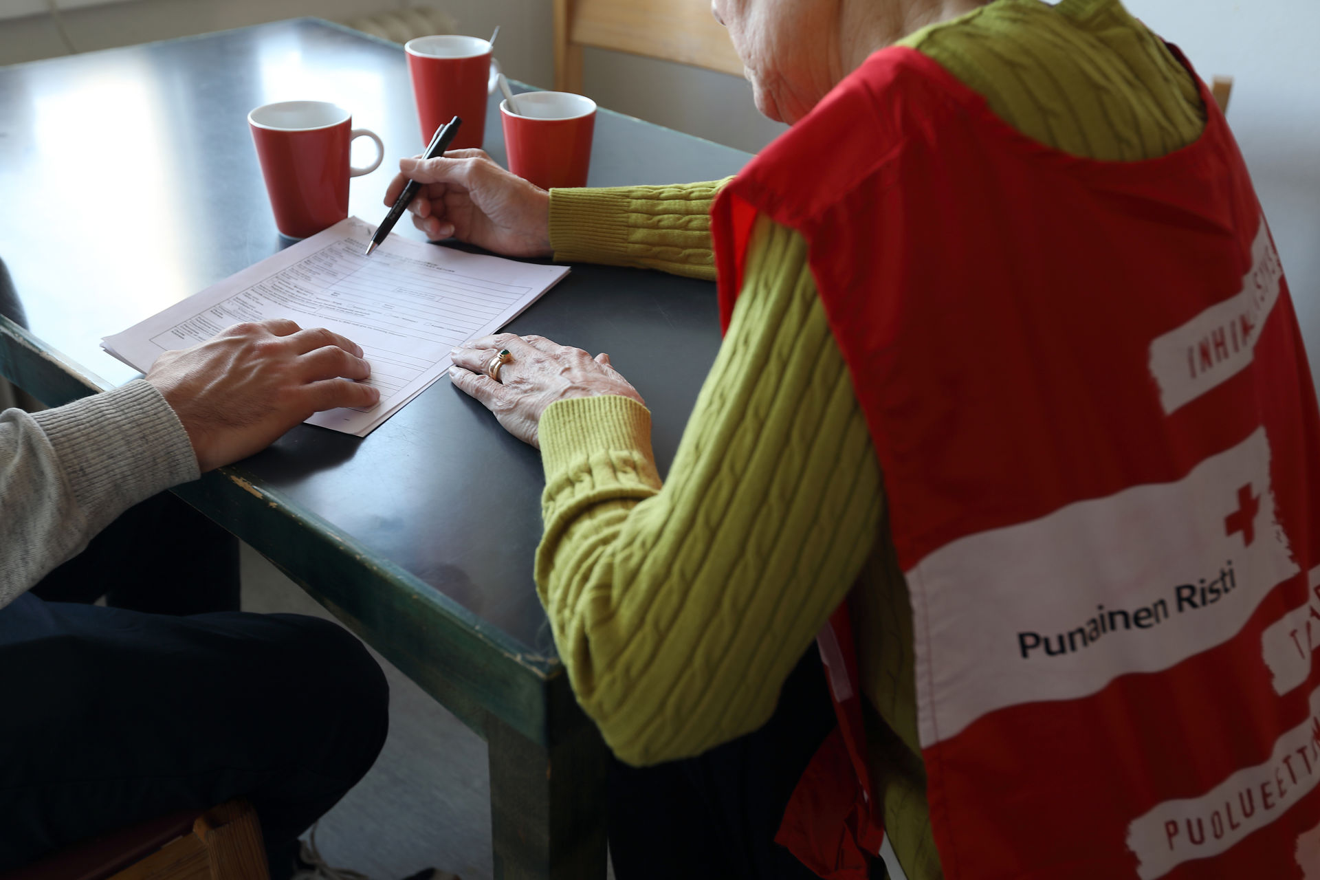 A Finnish Red Cross volunteer helping a person fill in a form.