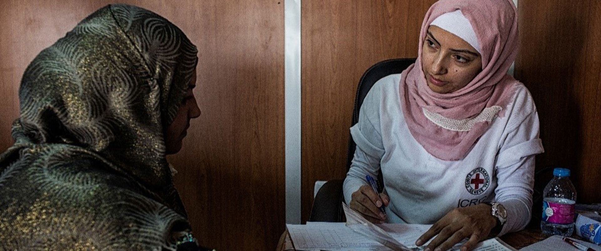A Red Cross employee talking with a person and taking notes.