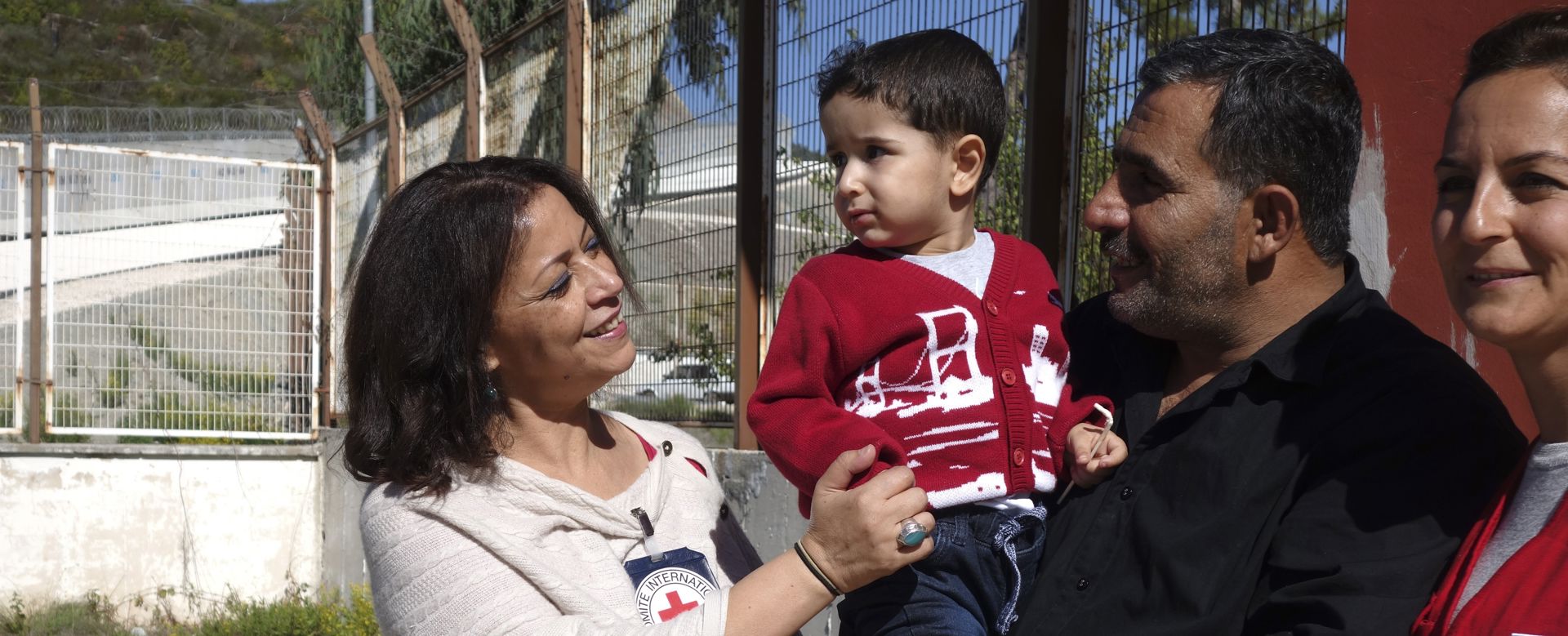 Restoring and maintaining family linksRed Cross and Red Crescent workers meeting a family with children outdoors.