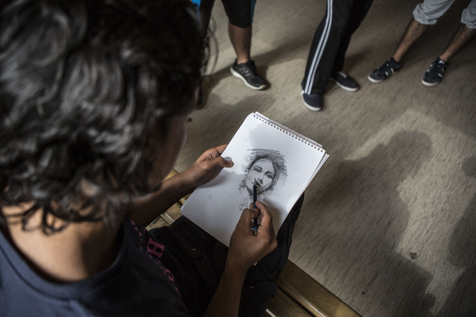 A portrait drawing in a person's hand.