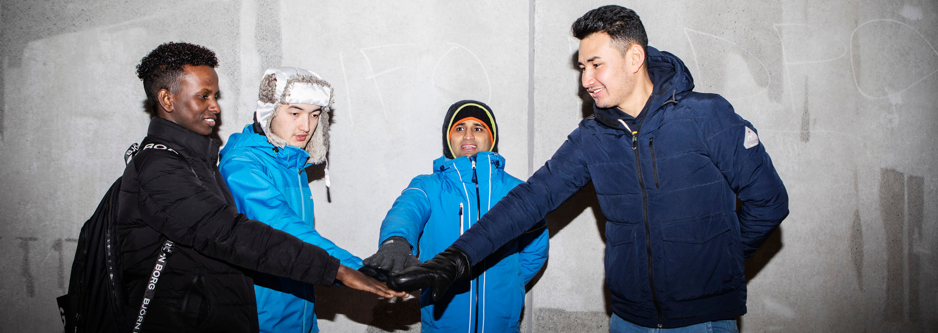 Four young people have put their hands together in the middle of a circle.