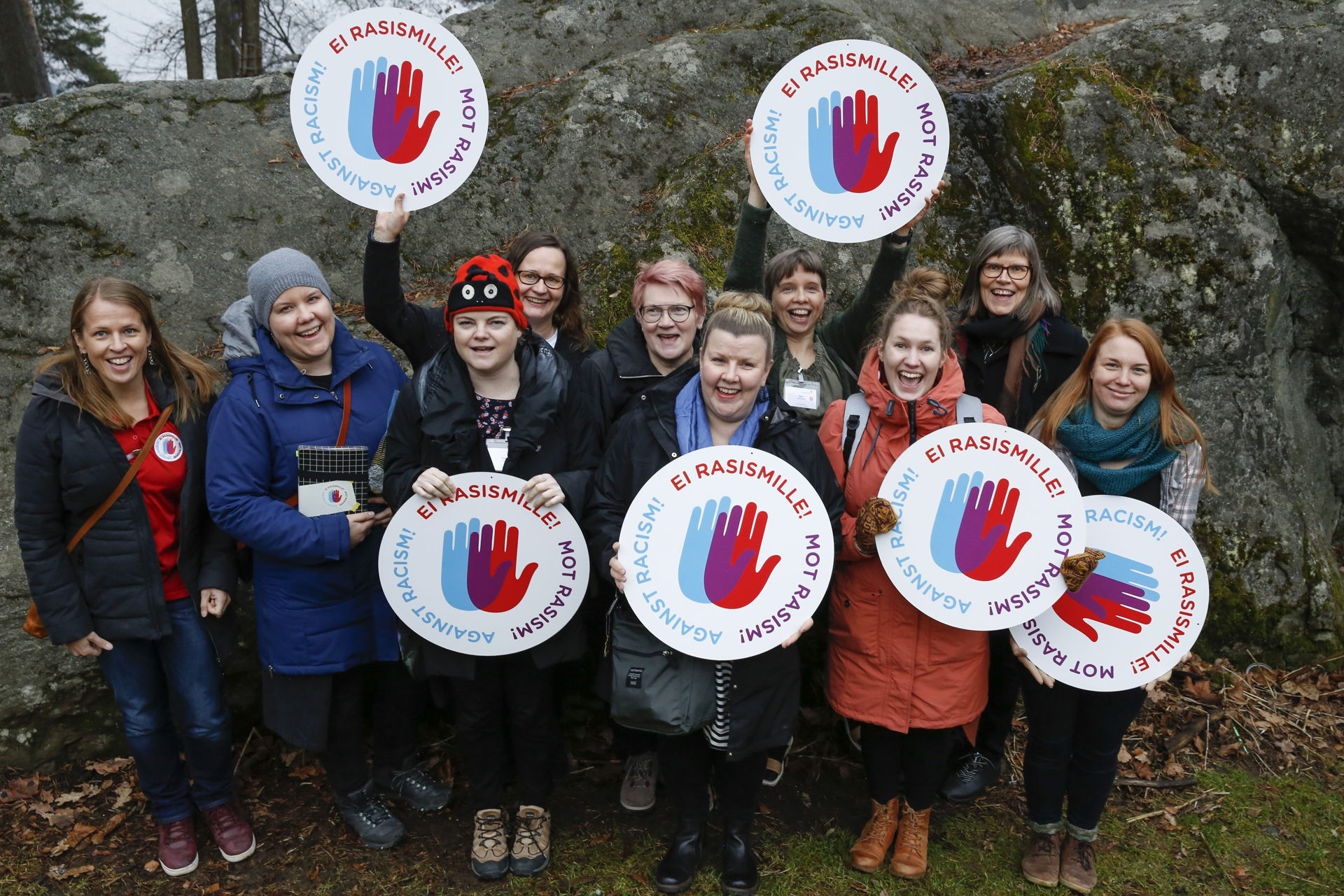 Group photo of immigration work trainers outdoors. They are holding anti-racism campaign logos in their hands.