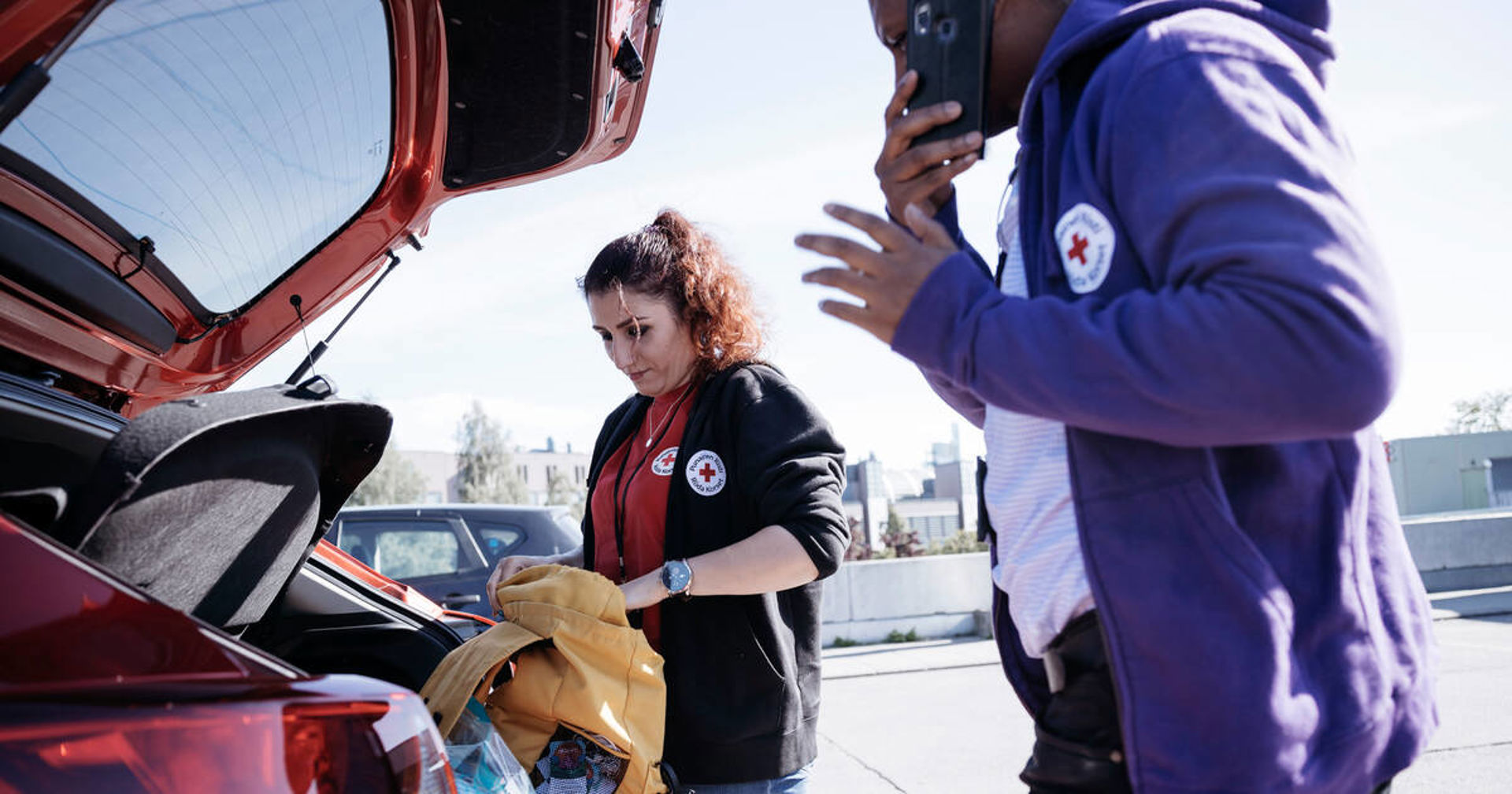 Two Red Cross volunteers packing a car.