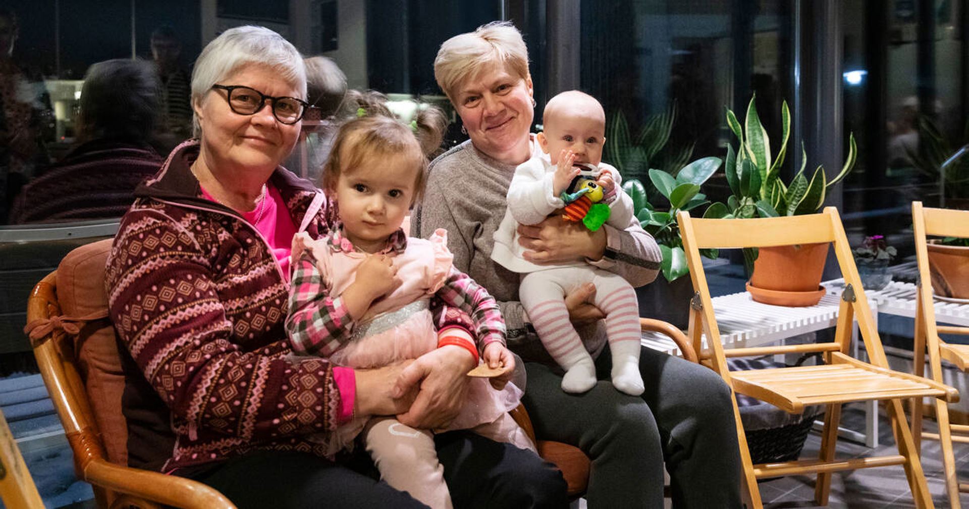 Two adults with children in their laps smiling at the camera.