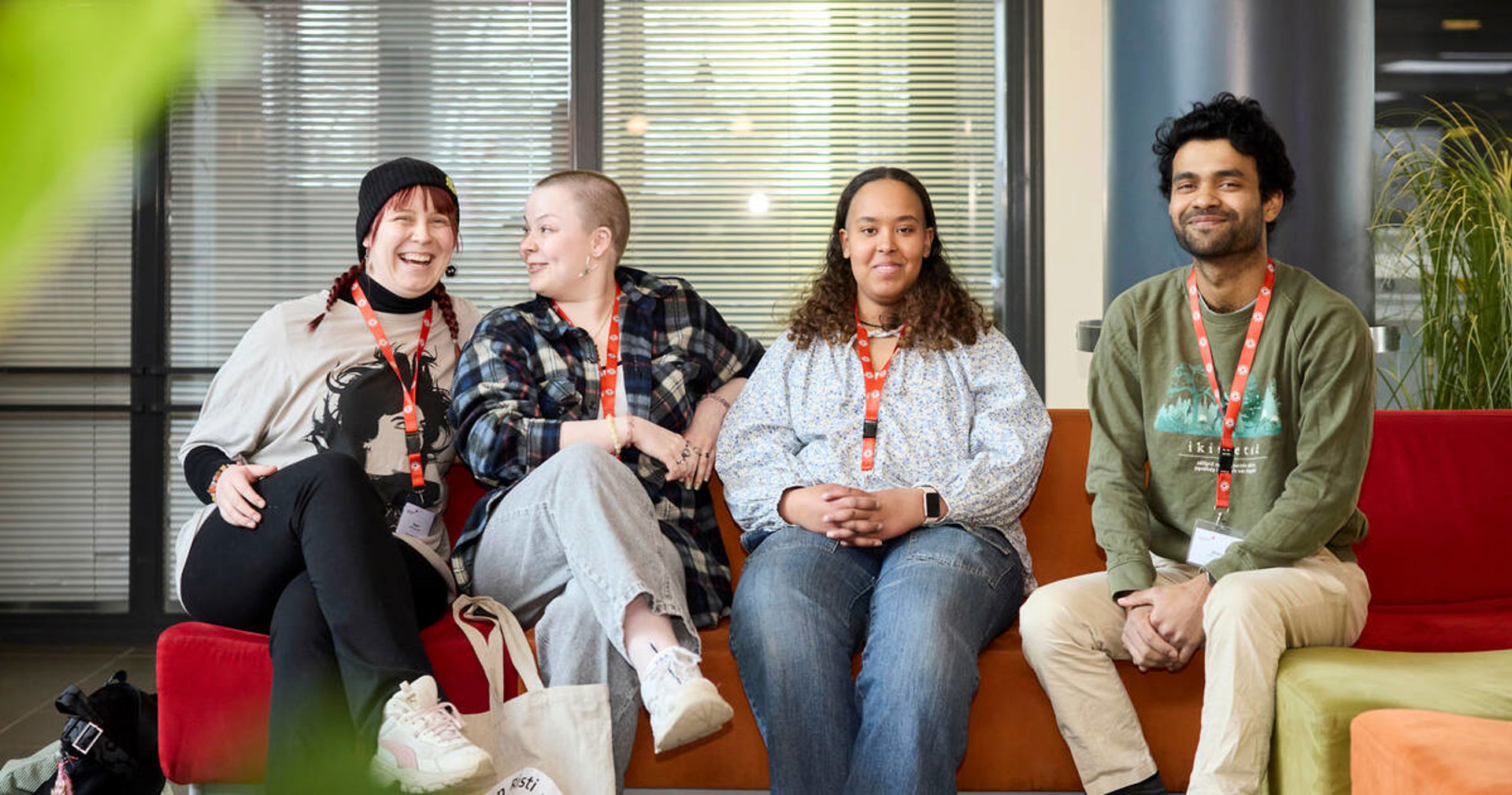 Four young Red Cross volunteers are sitting on a sofa and smiling at the camera.