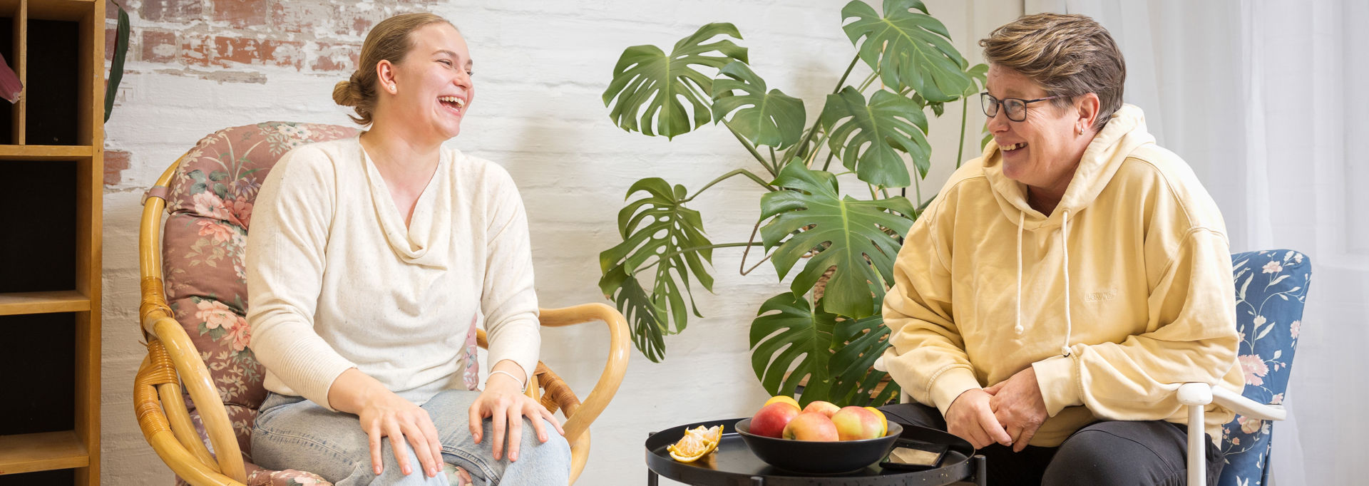 Two people are laughing around the coffee table.