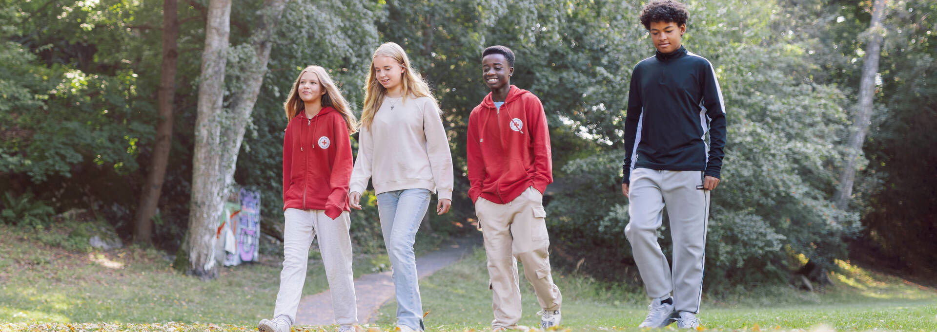 Four young people are walking outside and smiling.