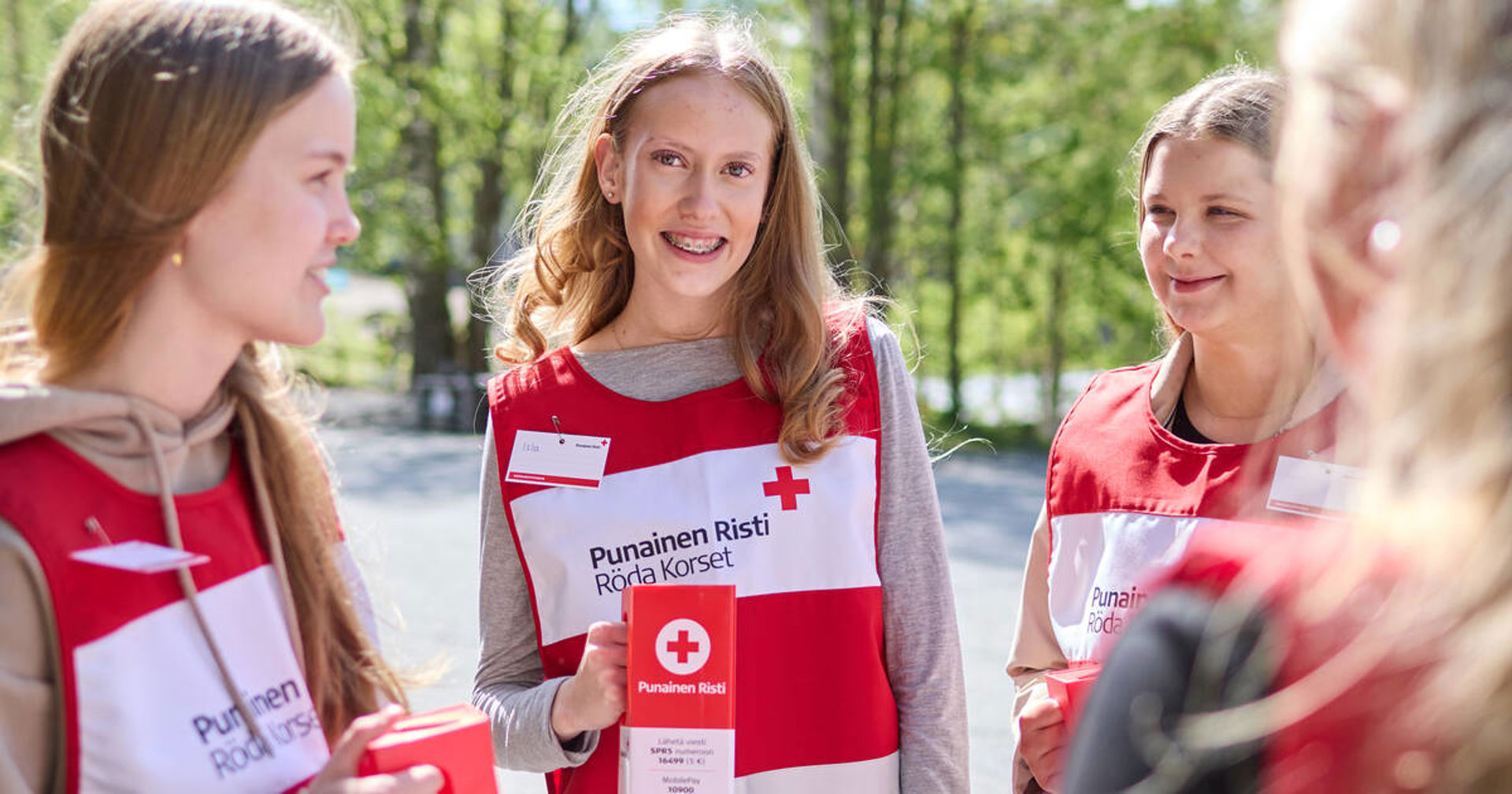 Three young people wearing collection vests and holding collection boxes in their hands.