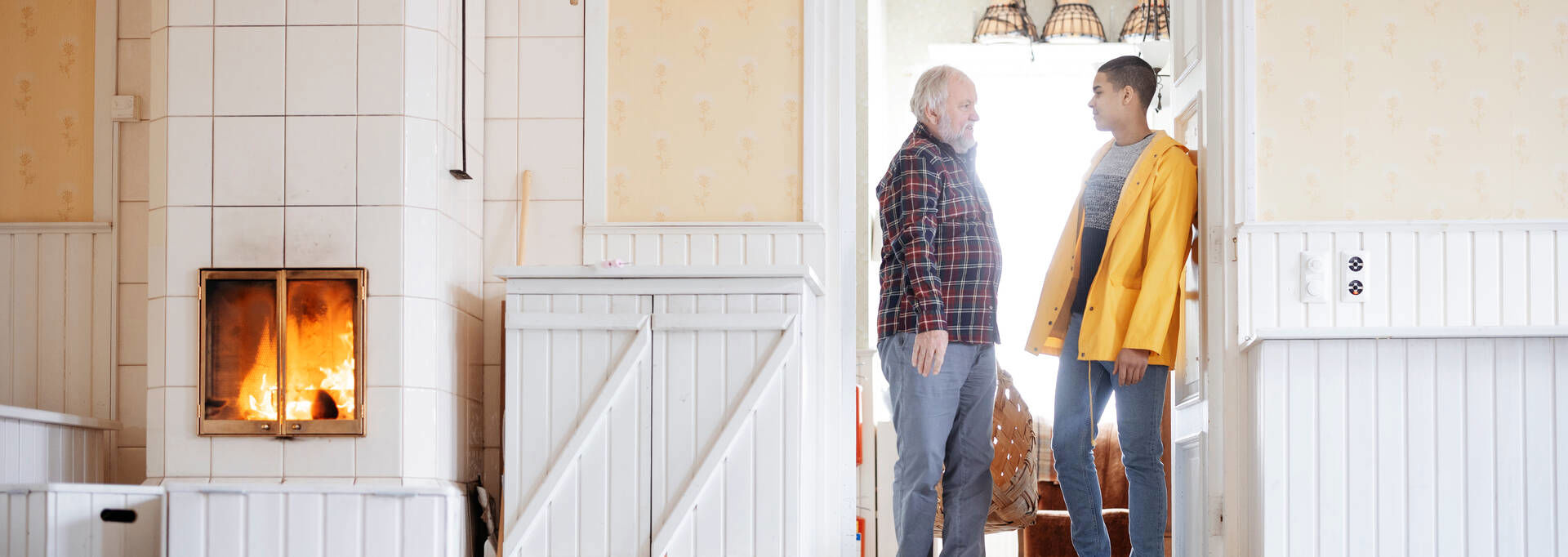 Two people looking at each other at a door next to a fire place.