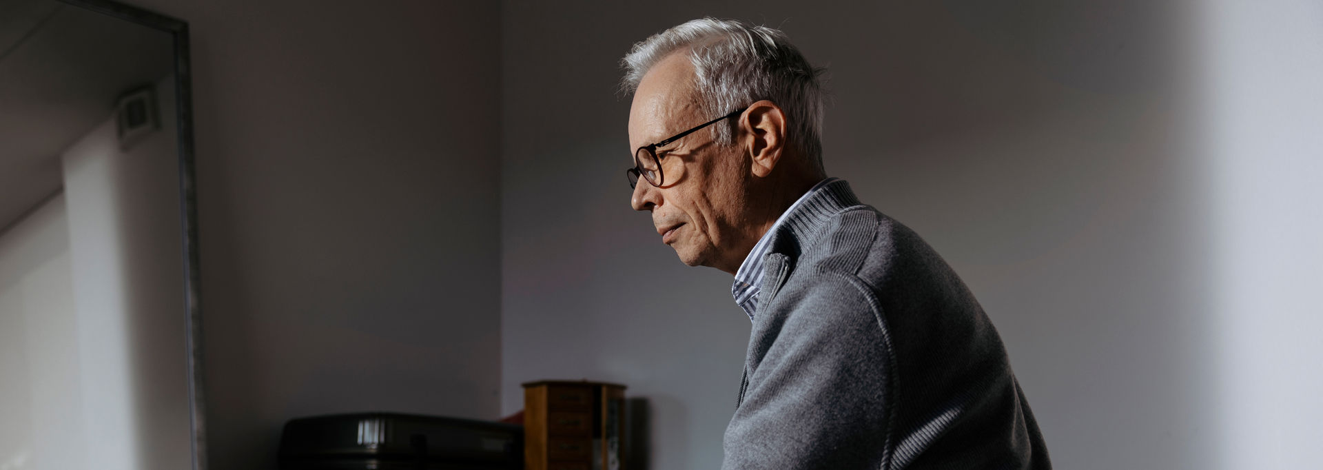 An older person sitting on a bed.